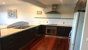 a kitchen with black cabinets and a sink at Coastal Escape in Tura Beach
