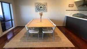 a dining room table with chairs and a clock on the wall at Coastal Escape in Tura Beach