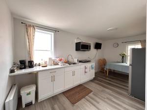 a kitchen with white cabinets and a large window at Garden View near Confederation Bridge and Beaches in Borden-Carleton