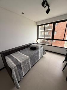 a bedroom with a bed and a large window at Flat completo e aconchegante em Caruaru in Caruaru