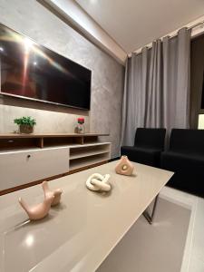a living room with a tv and a table at Flat completo e aconchegante em Caruaru in Caruaru