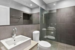 a bathroom with a white sink and a toilet at Pelicans at the Ozone in Queenscliff +10 photos