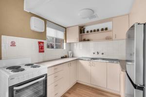 a kitchen with white appliances and white cabinets at Hydra 8 in Merimbula