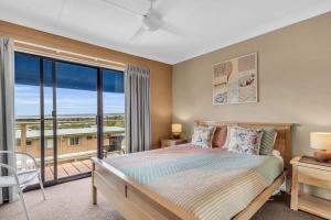 a bedroom with a bed and a large window at Hydra 8 in Merimbula