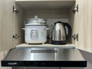 a coffeemaker and a slow cooker sitting in a cabinet at DG Coastal Comfort near Alona Beach - Pool, Gym and Play area in Dauis