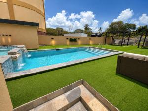a swimming pool with green grass next to a building at The Hive Boutique Hotel Pool Suite 108 in Scarborough