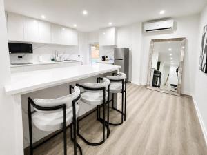 a white kitchen with a counter and stools in it at The Hive Boutique Hotel Pool Suite 108 in Scarborough