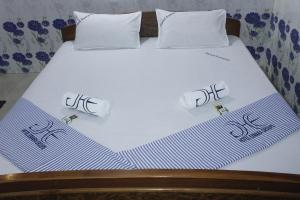 a bed with white sheets and pillows on it at Hotel Eswara Temple Stay in Kumbakonam