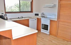 a kitchen with white appliances and wooden cabinets at Laura's Pambula Beach in Pambula Beach