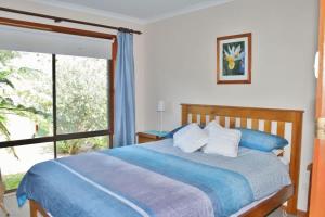 a bedroom with a bed and a large window at Laura's Pambula Beach in Pambula Beach +6 photos