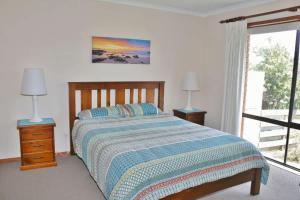 a bedroom with a bed and two lamps and a window at Laura's Pambula Beach in Pambula Beach