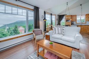 a living room with a couch and a table at Panoramic View 2BR FP BBQ Terrace - Upper in Petite-Rivière-Saint-François