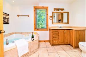 a bathroom with a tub and a sink and a toilet at Charlevoix 4BR Cottage Hot Tub & Game Room 12 in Petite-Rivière-Saint-François