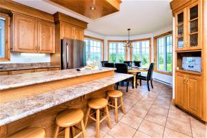 a kitchen with wooden cabinets and a bar with stools at Charlevoix 4BR Cottage Hot Tub & Game Room 12 in Petite-Rivière-Saint-François