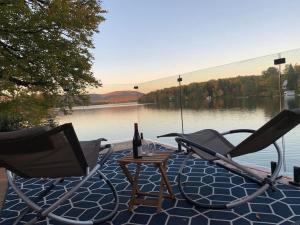 a couple of chairs and a table with a bottle of wine at Lakefront Chalet Hot Tub & Fire Pit Sleeps 6 in Saint-Raymond