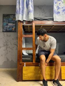 a man sitting on top of a bunk bed at Chamos Hostel Cultural in Arraial do Cabo