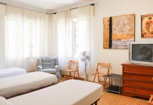a bedroom with two beds and a tv and chairs at Sanremo Apartments - Ortensia in Sanremo