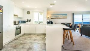a kitchen with white cabinets and a table and chairs at Quarterdeck 6 in Tura Beach