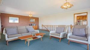 a living room with a couch and two chairs and a table at SeaLeka 6 in Merimbula +8 photos