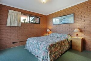a bedroom with a bed and a brick wall at SeaLeka 6 in Merimbula