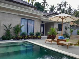 a house with a pool and two chairs and an umbrella at Villa KARISMA Candidasa in Candidasa