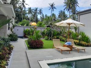 a patio with two chairs and an umbrella next to a pool at Villa KARISMA Candidasa in Candidasa
