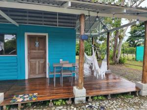 a blue house with a wooden deck with a table and chairs at El Carao in Talamanca