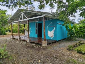 a blue tiny house with a porch at El Carao in Talamanca +10 photos