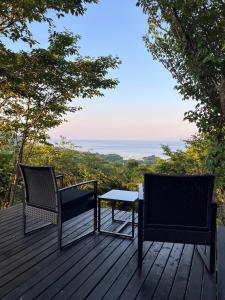 two chairs and a table on a wooden deck at Maison N in Shimoda