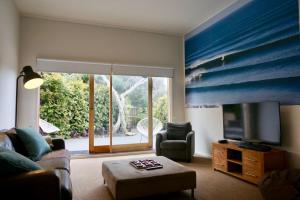 a living room with a couch and a television at Sand Dunes in Point Lonsdale