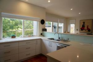 a kitchen with white cabinets and a sink and two windows at Sand Dunes in Point Lonsdale