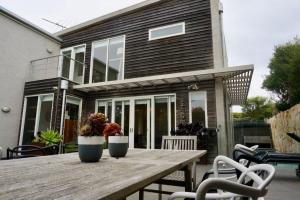 a wooden table in front of a house with two plants at Sand Dunes in Point Lonsdale