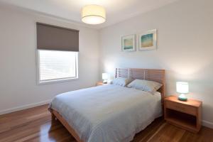 a bedroom with a bed with two lamps and a window at Taworri in Queenscliff +8 photos