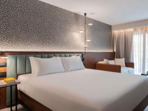 a hotel room with a large white bed and a chair at Novotel Malta Sliema in Il-Gżira