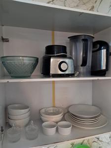 a kitchen shelf filled with dishes and a toaster at Conexão Cariri in Juazeiro do Norte