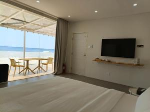 a room with a bed and a table with a television at Andante Beach Resort Batangas in San Luis