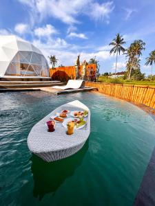 a tray of food on a table in the water at Triyana Resort and Glamping Carangsari Bali in Payangan