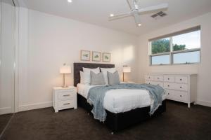 a white bedroom with a bed and a window at Margaret House | Elegant City-Fringe Escape in North Adelaide