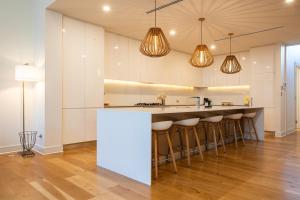 a kitchen with white cabinets and a counter with bar stools at Margaret House | Elegant City-Fringe Escape in North Adelaide +7 photos