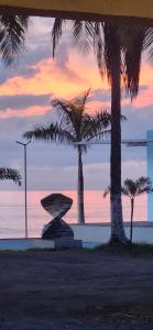 a sunset with two palm trees and the ocean at Sunrise Inn in Puerto Armuelles