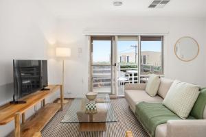 a living room with a couch and a tv at Sunset Drift Edithvale Steps to Beach in Edithvale