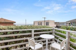 a patio with two chairs and a table on a balcony at Sunset Drift Edithvale Steps to Beach in Edithvale