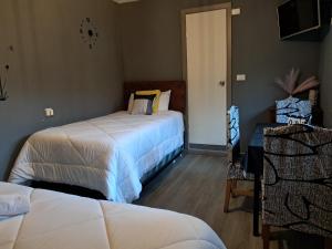 a bedroom with two beds and a table with a chair at El Laurel in Chillán