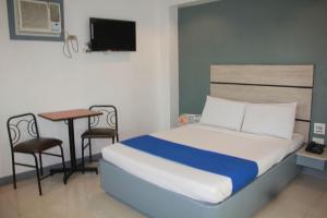 a bedroom with a bed and a table and a desk at Nice Hotel Arayat Cubao in Manila
