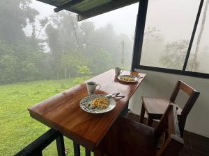 a wooden table with two plates of food on it at INTUS Lodge Rio Celeste in El pilon