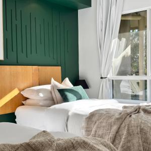 a bedroom with a green accent wall and a bed at Luxury 2 Bedroom apartment, Treetop views, Resort with 4 swimming pools in Cairns North
