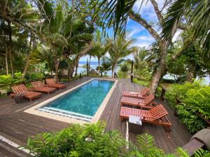 a deck with chairs and a swimming pool at Savasi Island Resort in Savusavu