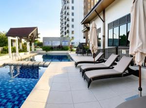 a pool with chaise lounge chairs next to a building at DG Coastal Comfort near Alona Beach - Pool, Gym and Play area in Dauis