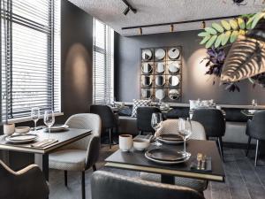 a dining room with tables and chairs and windows at Le Marin Hotel Rotterdam City - Handwritten Collection in Rotterdam