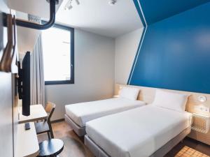 a hotel room with two beds and a tv at ibis budget Madrid Albasanz in Madrid